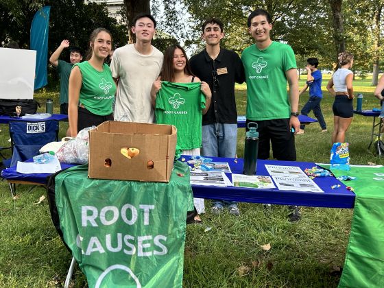 Alexi Mosu with a group of people at the Root Causes table