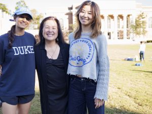 two female students smiling with professor Chow on Duke quad